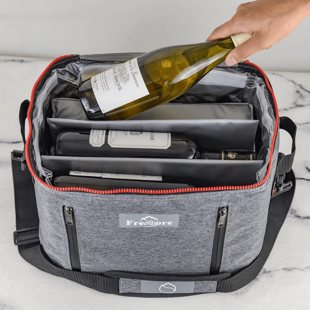 Gray wine cooler bag with a hand placing a bottle of wine inside on a marble surface.