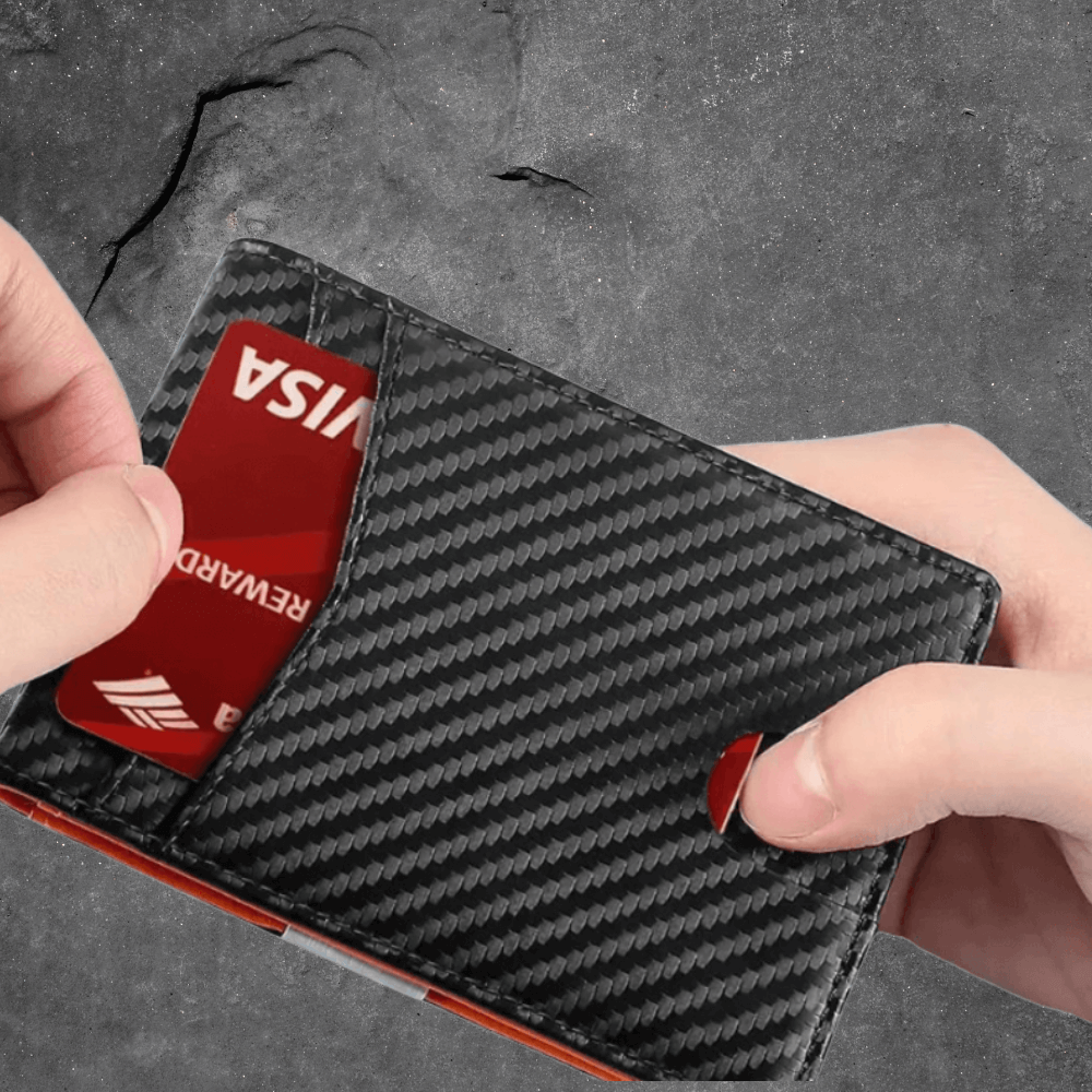 Carbon fiber wallet with a Visa card being inserted on a gray background