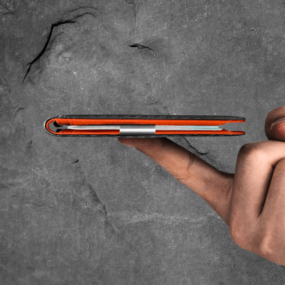 Hand holding a red and black phone case against a gray stone background