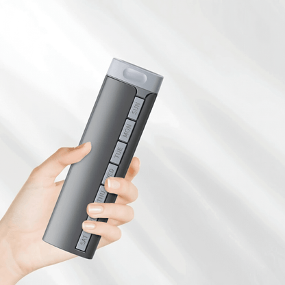 Hand holding a gray electronic device with buttons on a light gray background