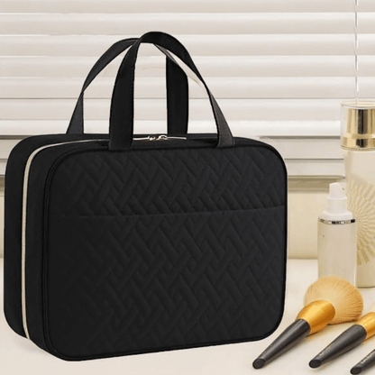 Black quilted makeup bag with cosmetic items on a light surface.