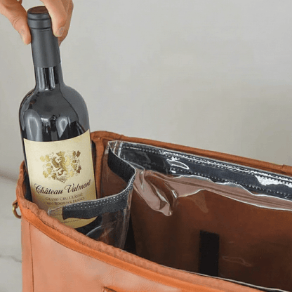 Bottle of Chateau Valmont wine being placed into a brown leather bag.