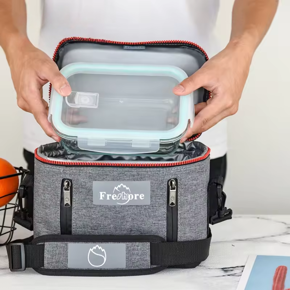 Person opening a gray cooler bag with a red interior, featuring the Freshpre brand.