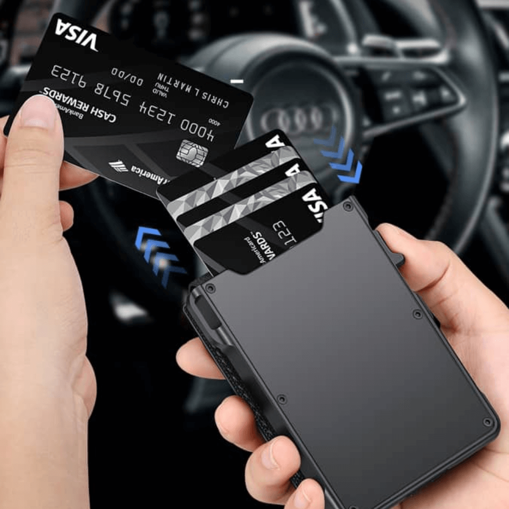 Person holding a black cardholder with multiple cards in front of an Audi car interior.