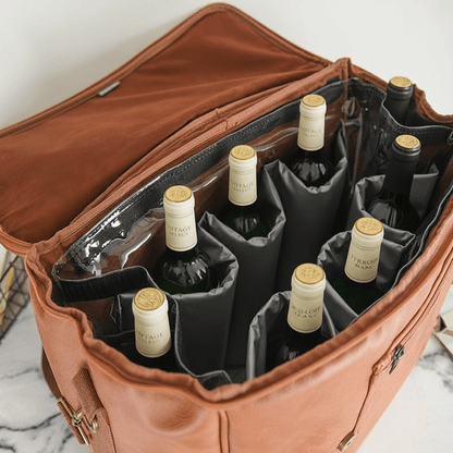 Brown leather wine carrier with six bottles of wine on a marble surface