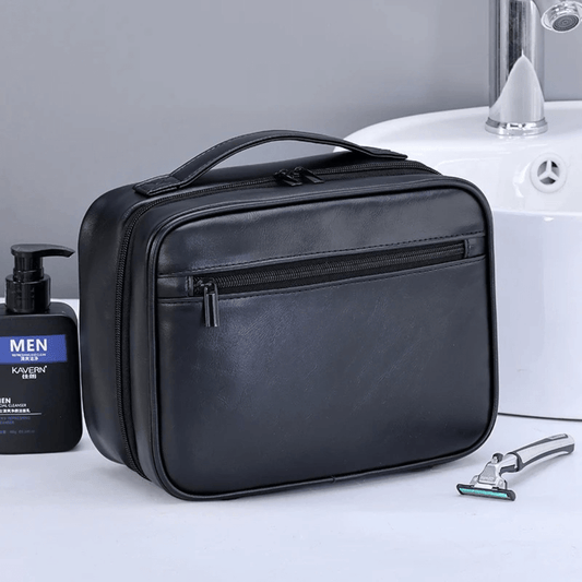 Black toiletry bag on a bathroom counter with a bottle and razor.
